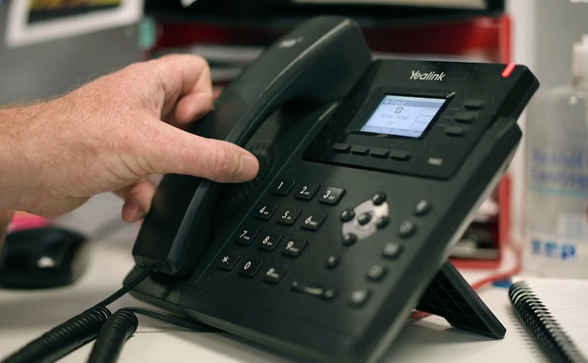 Hand picking up office phone to ask for material advice 