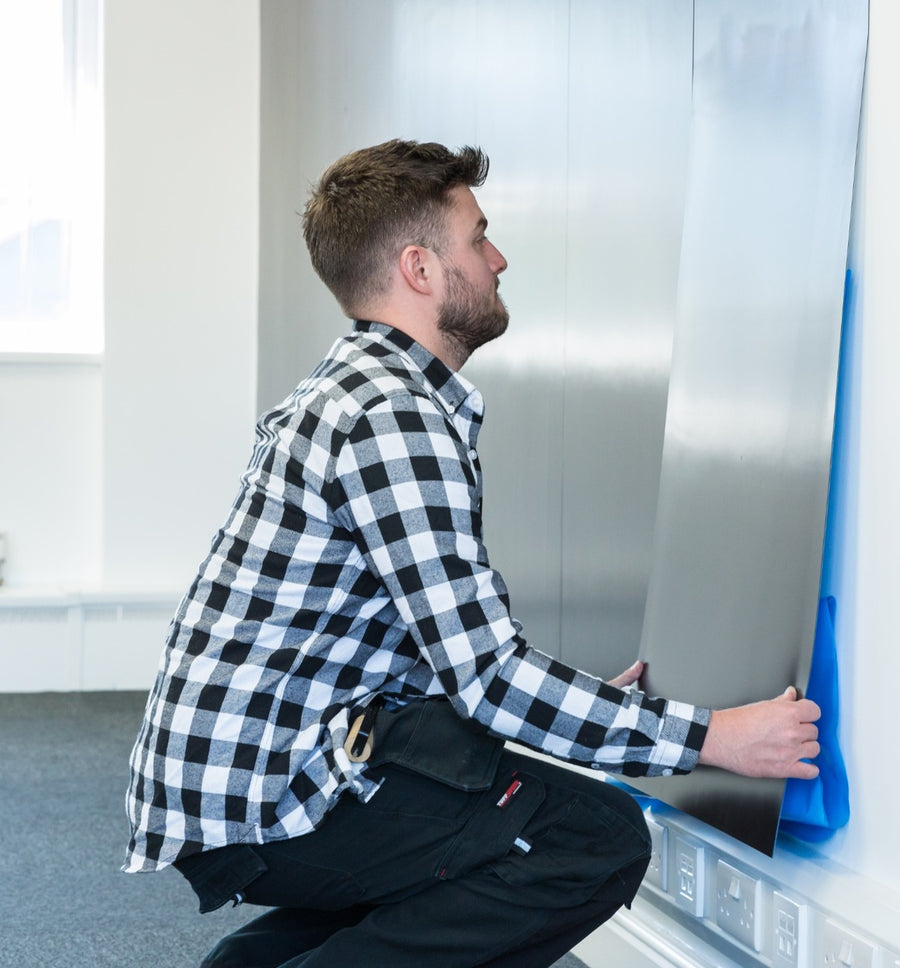 Installer applying magnetic receptive material to a wall surface 